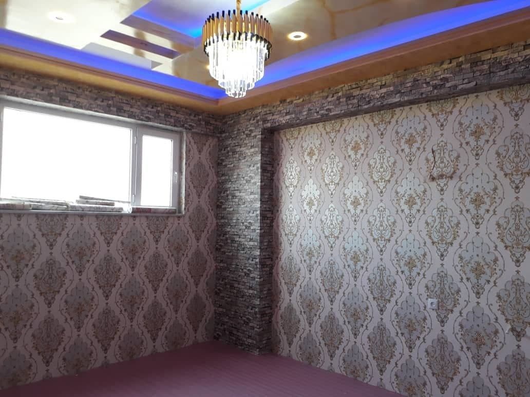 Room with damask and brick-effect wall murals under a chandelier